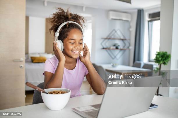 cute young girl eating breakfast and surfing the net on the laptop - children cooking school stock pictures, royalty-free photos & images