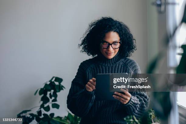 beautiful woman using a digital tablet at home - african american woman with tablet stockfoto's en -beelden