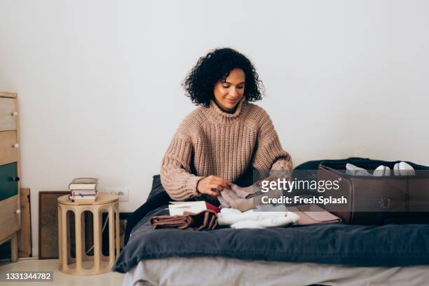 smiling woman packing her suitcase for winter holidayâ at home - suitcase packing stockfoto's en -beelden