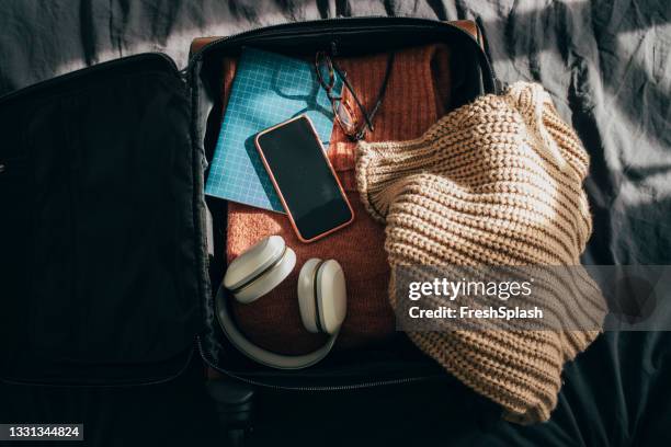 öffnen sie das gepäck mit kleidung und anderen objekten auf dem bett zu hause - open travel bag stock-fotos und bilder