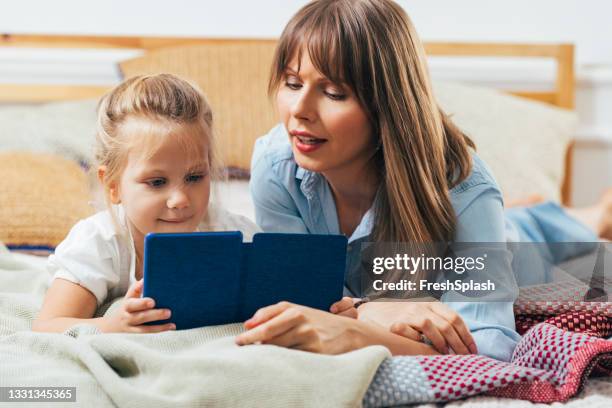 madre e hija pasan tiempo de calidad en casa - lector de libros electrónicos fotografías e imágenes de stock