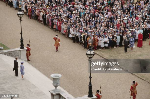 High angle view showing British Royals Queen Elizabeth II and Prince Philip, Duke of Edinburgh on the steps before their guests at the garden party...