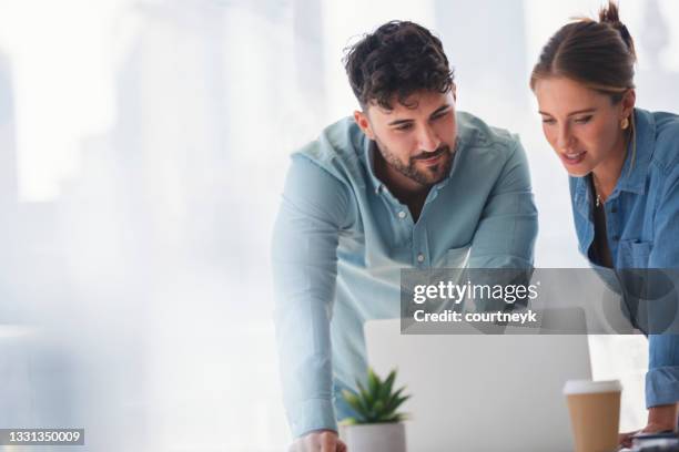 businessman and businesswoman working on a laptop computer. - business couple showing stockfoto's en -beelden