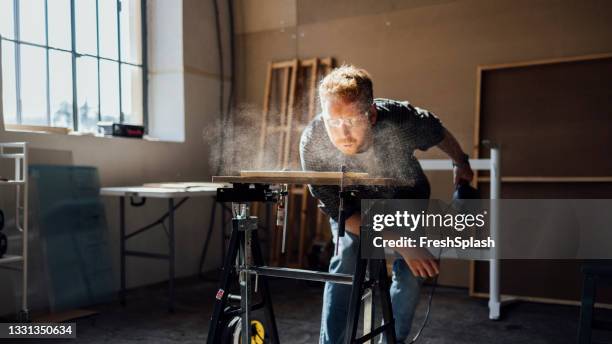 carpenter blowing dust from wooden plank - wood workshop stock pictures, royalty-free photos & images
