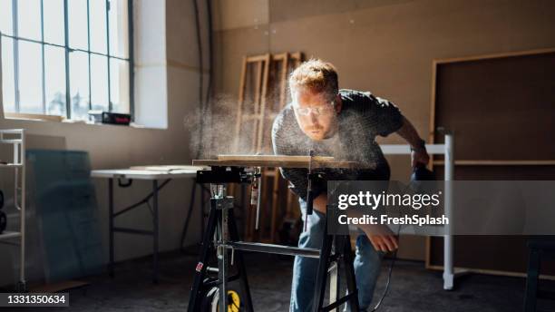 carpenter blowing dust from wooden plank - blowing sawdust stock pictures, royalty-free photos & images