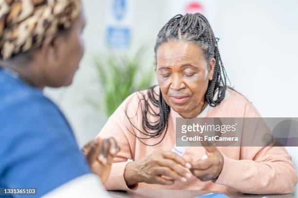 elderly woman discussing treatment with nurse - diabetes pills stock pictures, royalty-free photos & images