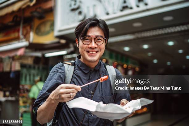 young handsome man enjoying hong kong local street food joyfully in street - comida china - fotografias e filmes do acervo