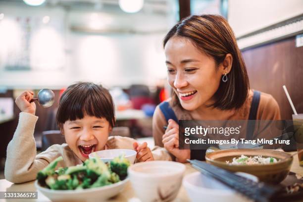mom & daughter enjoying meal in restaurant - asia child lifestyle stock-fotos und bilder