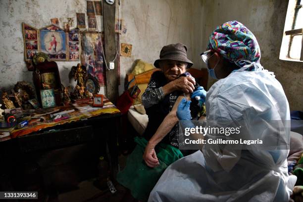 Elizabeth Romero a nursing assistant, gives a shot of the second dose of the Sinovac COVID-19 vaccine to Dolores Mican at her house during a...