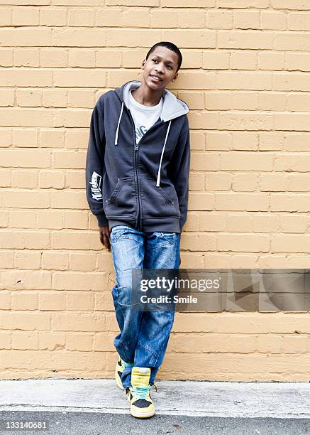 boy leaning against brick wall - boy jeans stockfoto's en -beelden