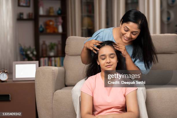 mother gives oil head massage to her daughter at home - indian mother stockfoto's en -beelden