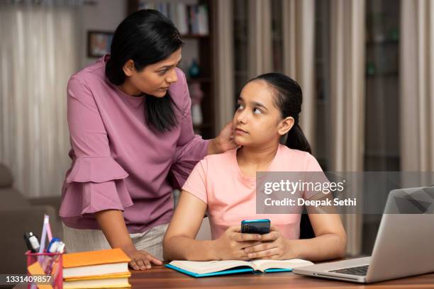 mother catches daughter using phone while studying - repreensão imagens e fotografias de stock