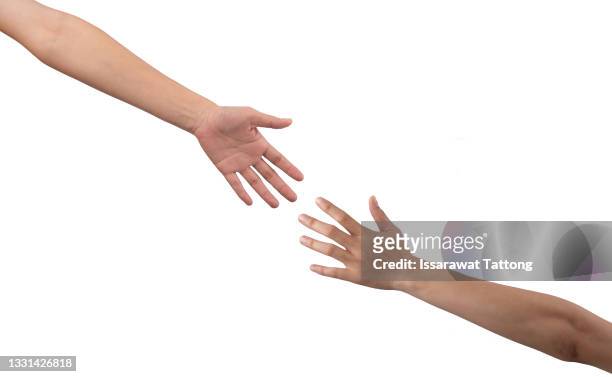 closeup shot of two unrecognisable people reaching for each other with their hands - hand reichen stock-fotos und bilder