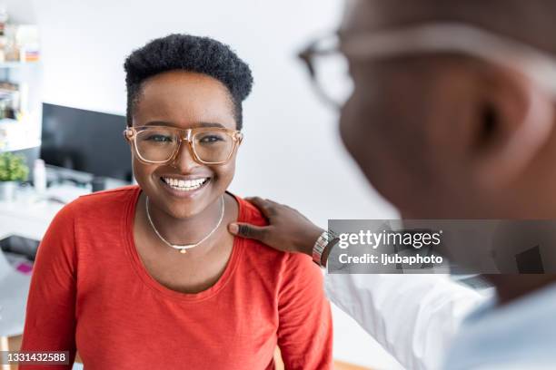 female patient listens carefully to mid adult male doctor - man touching shoulder stock pictures, royalty-free photos & images