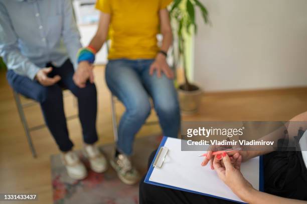 una psicoterapeuta que toma notas mientras habla con dos mujeres que forman parte de la comunidad lbgt. - ets fotografías e imágenes de stock