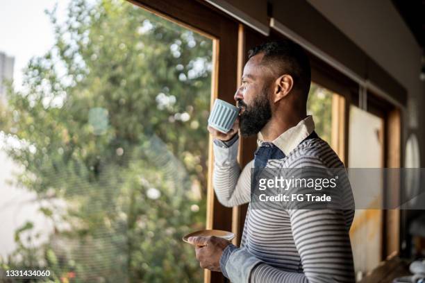 mature man drinking tea and contemplating at home - man resting stock pictures, royalty-free photos & images