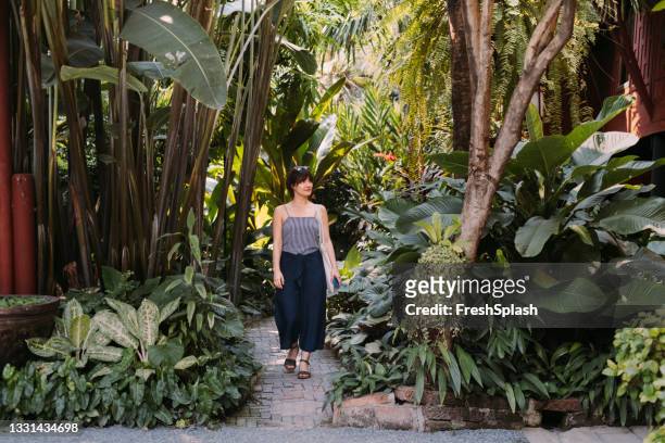 schöne junge frau macht einen spaziergang in einem botanischen garten in bangkok - botanischer garten stock-fotos und bilder
