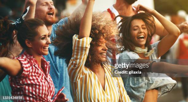 group of friends dancing at a concert. - zomer muziek stockfoto's en -beelden