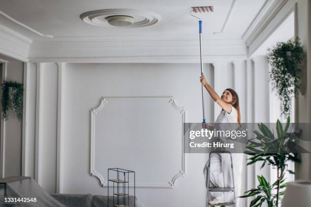 woman painting ceiling with paint roller - painted ceiling stock pictures, royalty-free photos & images