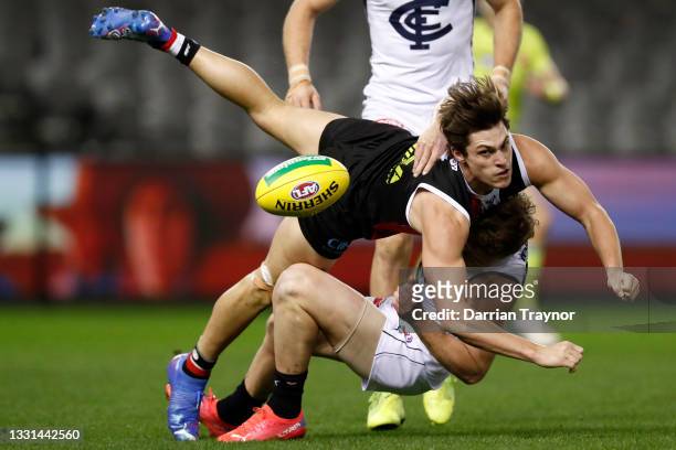 Jack Steele of the Saints handballs while being tackled by Jack Newnes of the Blues during the round 20 AFL match between St Kilda Saints and Carlton...