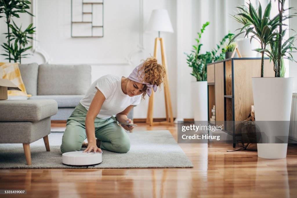 Woman turning on robotic vacuum cleaner