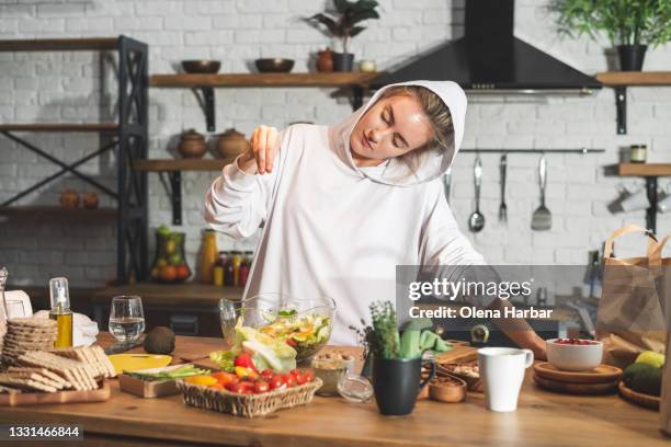 home stylish cozy kitchen, where a girl in a white hoodie spices a ready-made fresh vegetable salad - i love my wife pics stock pictures, royalty-free photos & images