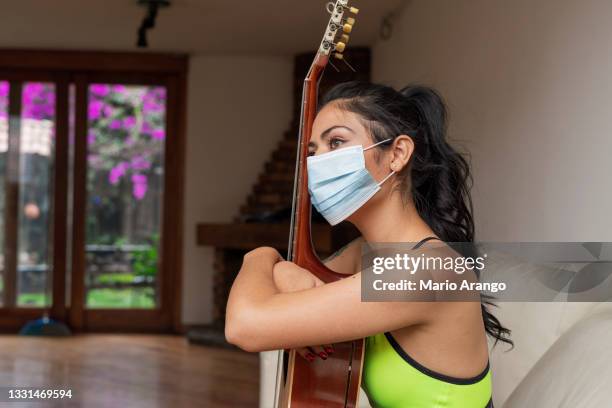 beautiful woman sitting with an attitude of bored by the isolation generated by covid 19 while holding her guitar and wearing her mask - masked musicians bildbanksfoton och bilder