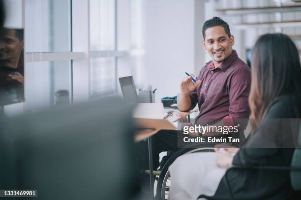 indian white collar male worker in wheelchair having cheerful discussion conversation with his female asain chinese colleague coworking in creative office workstation beside window - wheelchair office stock pictures, royalty-free photos & images