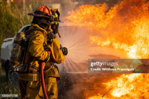 firefighters spraying water on burning car - carro de bombeiro fotografías e imágenes de stock