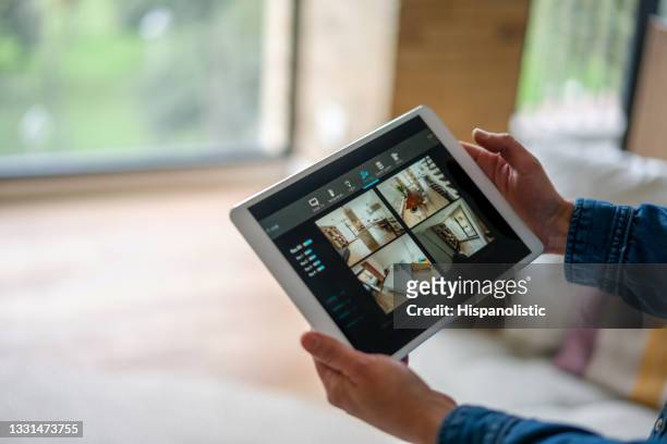 woman monitoring her house with a home security system - alarme imagens e fotografias de stock
