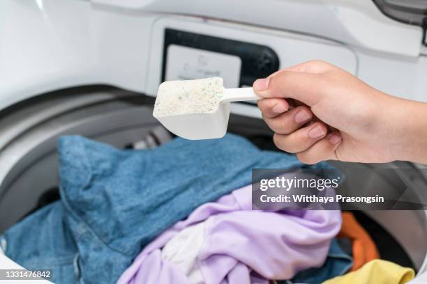 hand pouring detergent into the washing machine - detergente da roupa imagens e fotografias de stock