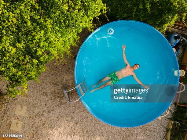 young man enjoying relaxing in small swimming pool - garden aerial view stock pictures, royalty-free photos & images