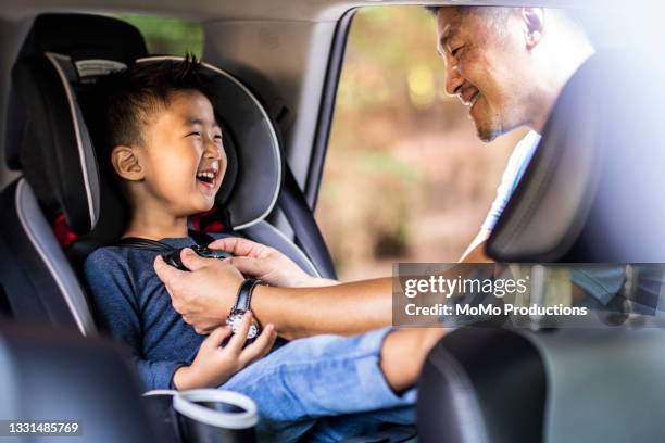 father buckling son in car seat - ドライブ旅行 ストックフォトと画像