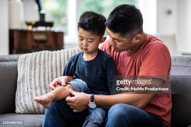 father putting band-aid on son - blue boy band stock pictures, royalty-free photos & images