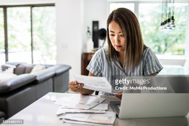 woman paying bills at home - asian finance photos et images de collection