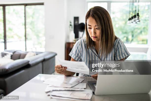 woman paying bills at home - debiteuren stockfoto's en -beelden