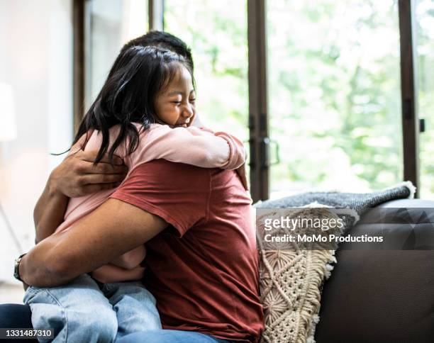 father embracing daughter at home - leanincollection stock pictures, royalty-free photos & images