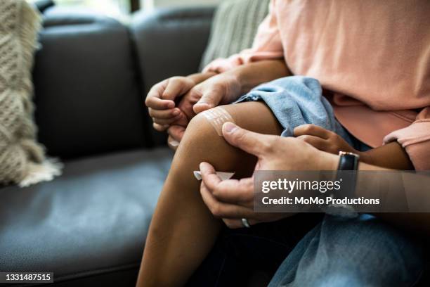 father putting band-aid on daughter - hand laceration stockfoto's en -beelden