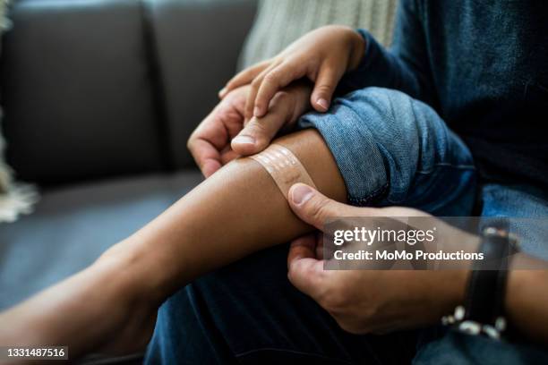 father putting band-aid on son - hand laceration stockfoto's en -beelden