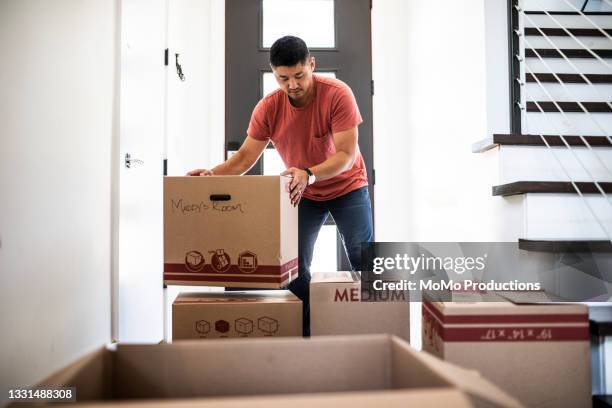 man lifting moving boxes at new home - box lifting technique stock-fotos und bilder