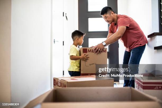 father and son lifting moving boxes at new home - on the move imagens e fotografias de stock