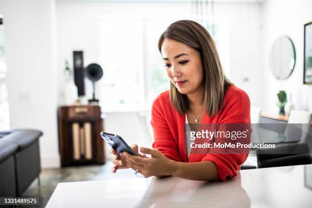 woman using mobile device at home - person looking at phone photos et images de collection