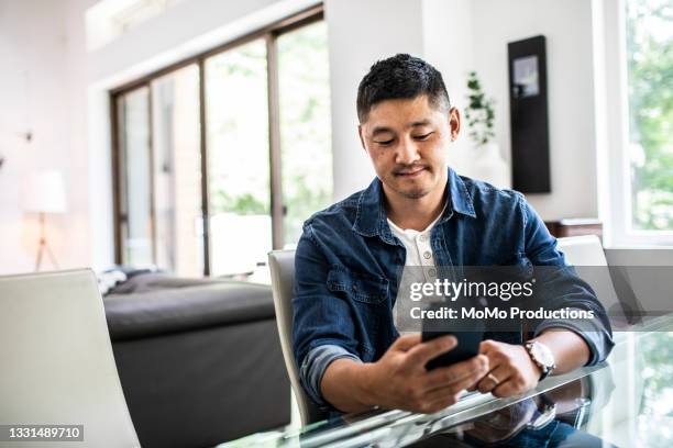 man using mobile device at home - korean ethnicity stock pictures, royalty-free photos & images