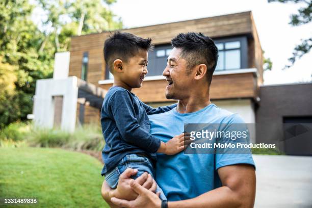 father holding son in front of modern home - monoparental fotografías e imágenes de stock