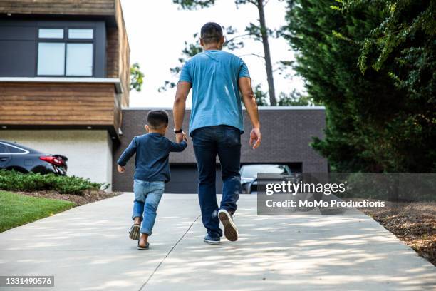 father walking up driveway with son - cars lifestyle stock pictures, royalty-free photos & images