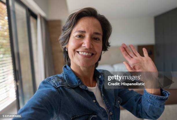 feliz mujer en casa saludando en una videollamada - autofoto fotografías e imágenes de stock