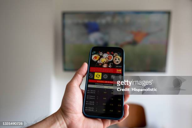 man watching a football match and gambling on a mobile app - 賭博 個照片及圖片檔