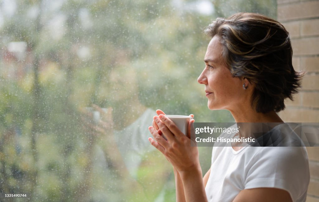 Woman drinking a cup of coffee while looking out of the window