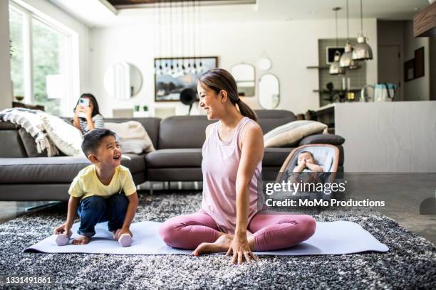mother doing yoga at home surrounded by children - vest stock pictures, royalty-free photos & images