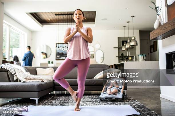 mother doing yoga at home surrounded by children - yoga rug photos et images de collection